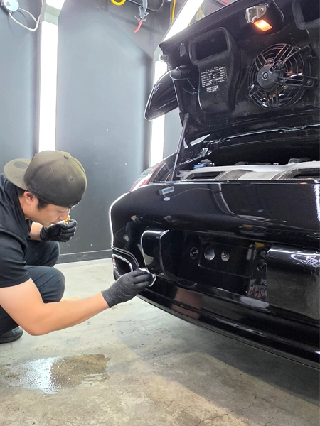 Technician ceramic coating on Porsche 911 rear bumper