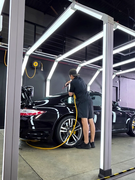 SPL technician performing machine paint correction on black Porsche