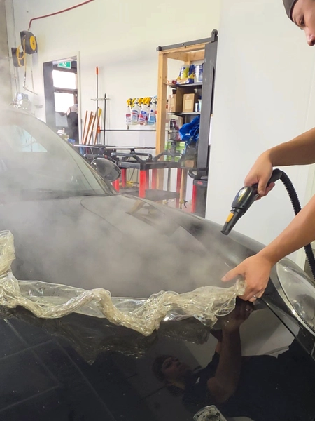 Technician carefully removing old PPF from Porsche 911